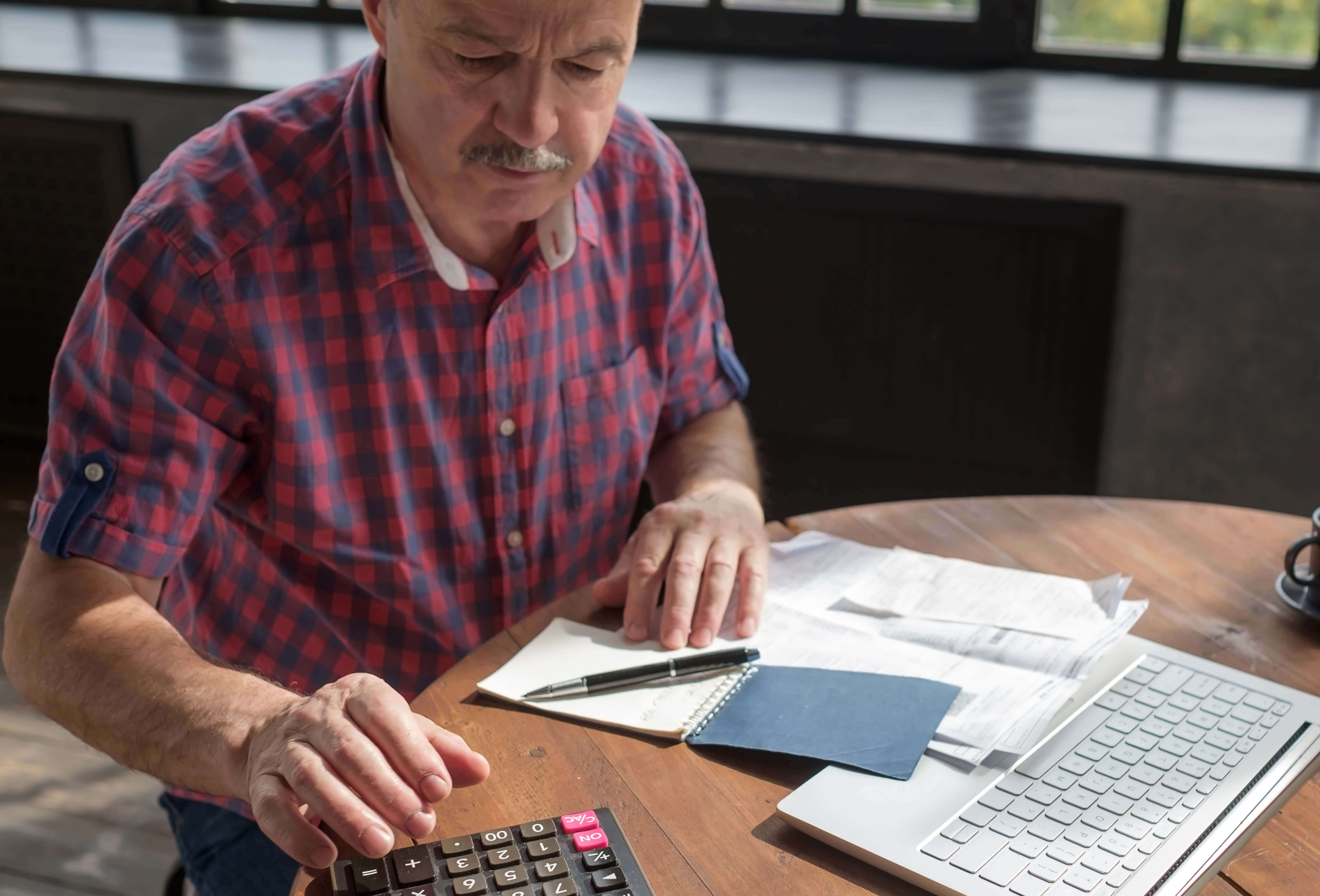 Man calculating his expenses at his kitchen table.